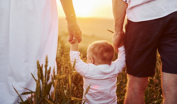 Bebe caminando de la mano de sus padres